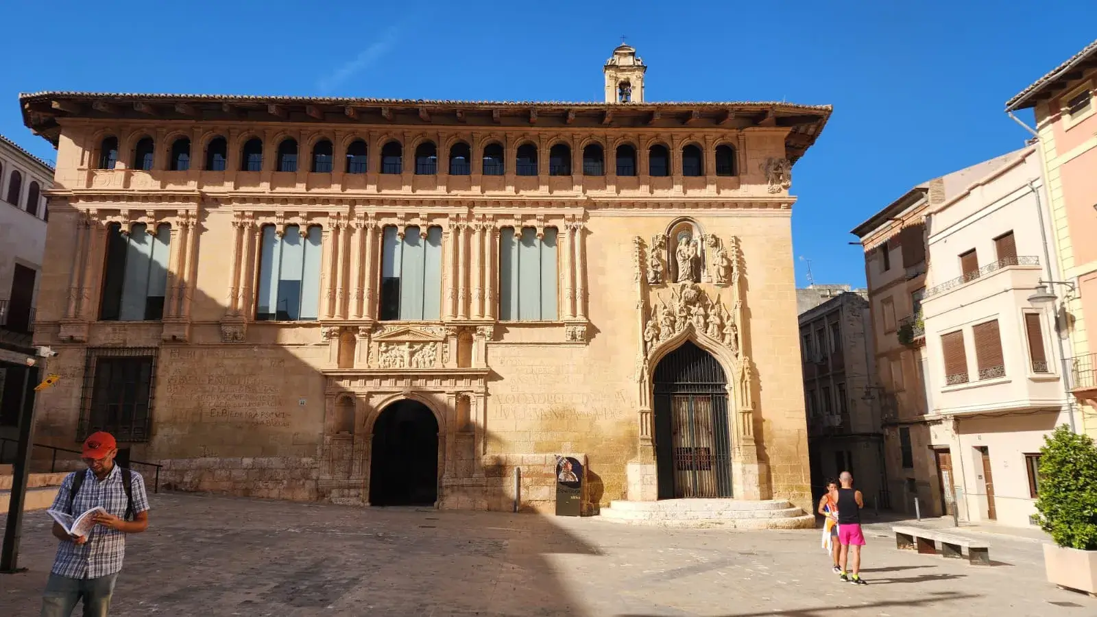 Fachada de palacio gótico en una plaza soleada de Xàtiva