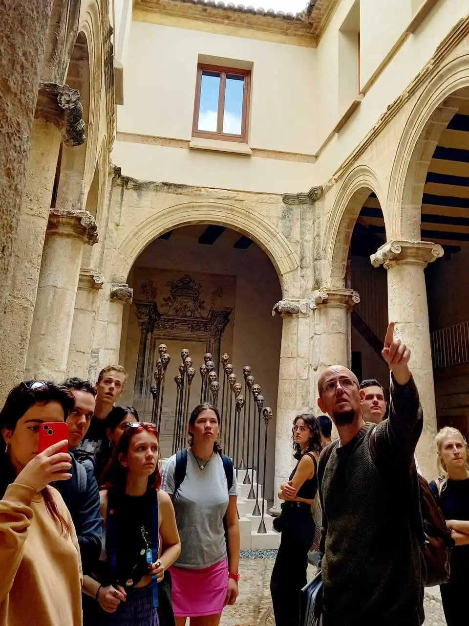 Jaume guiando a un grupo bajo los arcos tallados del Real Colegio del Patriarca